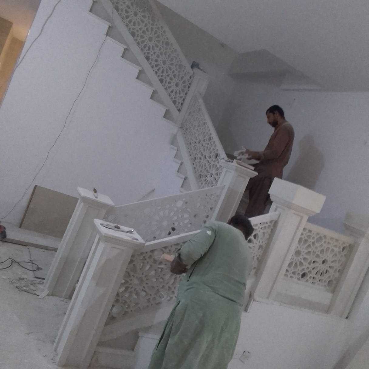 فنيّان ينفّذان درابزين درج بزخارف من الجبس