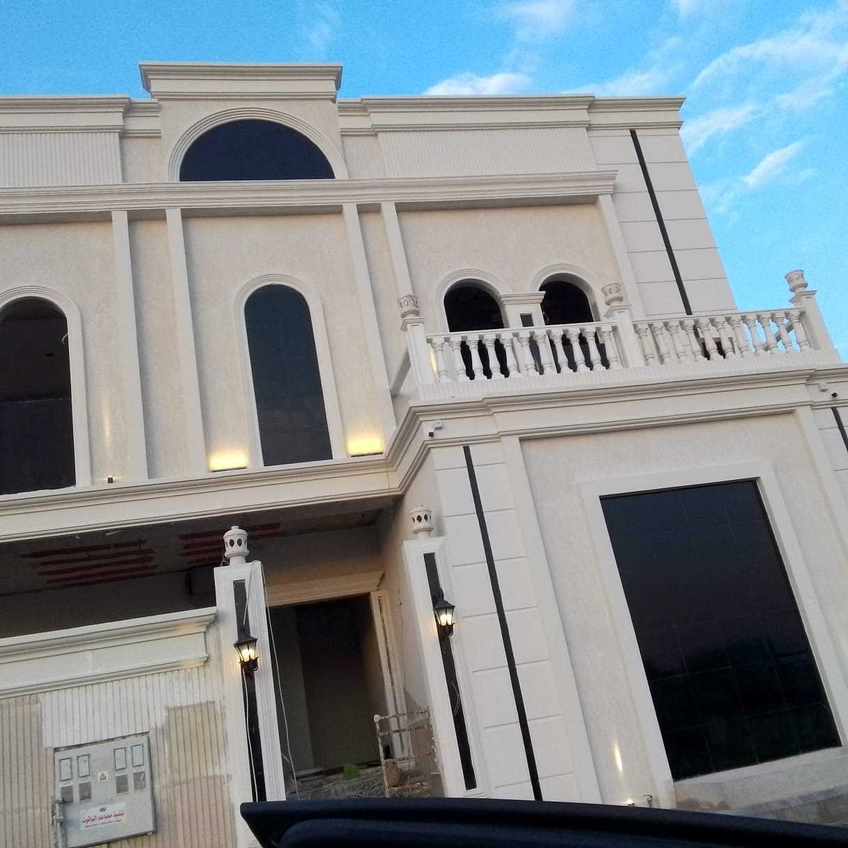 واجهة فيلا بتشطيب حجري فاتح ونوافذ مقوّسة
